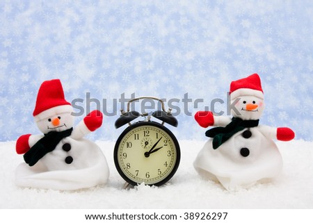 A black retro clock with a snowman sitting on snow background, winter time