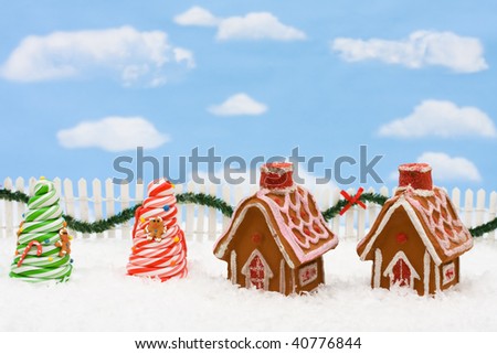 Gingerbread house on snow with a white picket fence with garland and sky background, gingerbread house