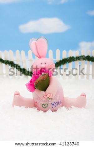 A pink bunny on a white picket fence with garland on a  sky background, Pink Bunny