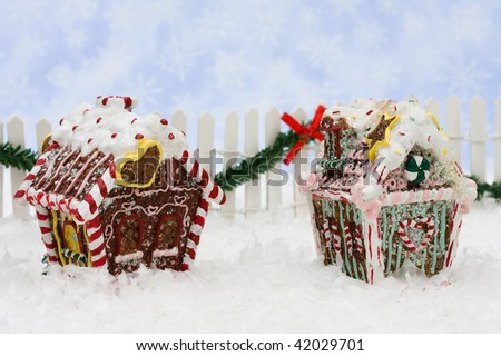 Gingerbread houses with a white fence and green garland on a snowflake background, gingerbread houses