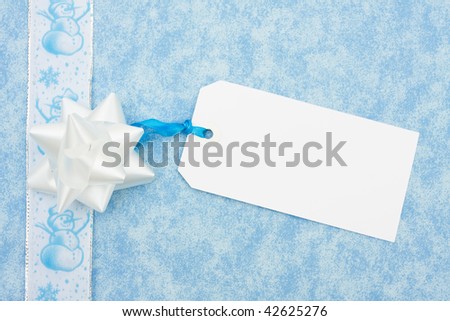 A blue ribbon bow sitting with a snowman ribbon on a blue background