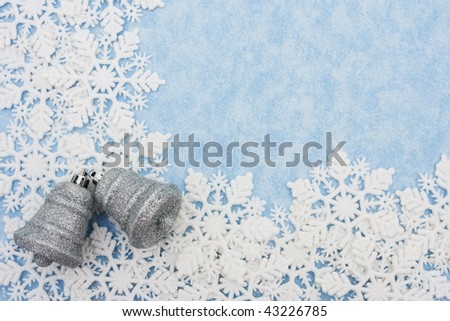 Snowflakes making a border with silver bells on a blue background, snowflake border