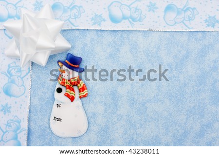 A white ribbon bow sitting with a snowman ribbon on a blue background
