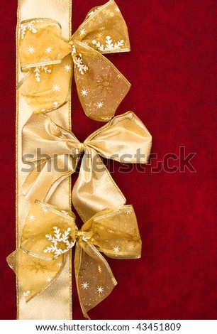 A gold ribbon bows sitting with a ribbon on a red background