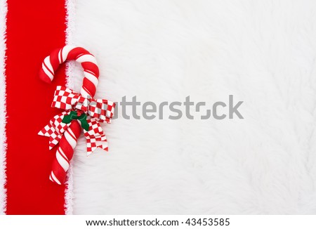 A candy cane with a red ribbon on a white fur background