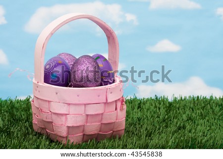 Wicker basket filled with Easter eggs on green grass background, Easter basket