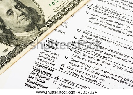 One hundred dollar bills sitting on tax papers, tax forms