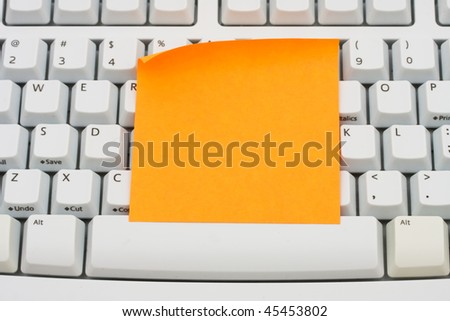 A blank orange sticky note sitting on a computer keyboard, computer note