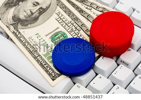 Poker chips and cash sitting on a computer keyboard, online poker