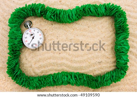 A green lei making a border on a sand background, Time to go on vacation