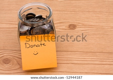 A jar full of change sitting on a wooden background, Please help by donating money