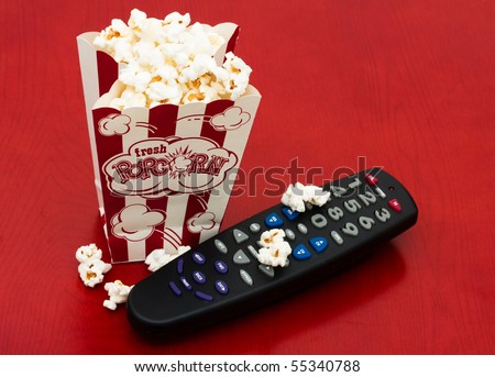 A red and white container of popcorn on a wood background, Home entertainment