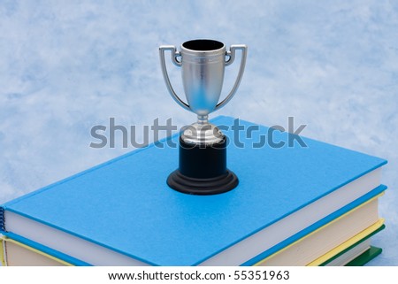 A stack of book with a trophy on a blue background, education award