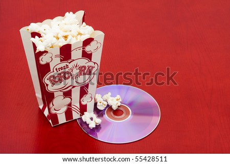 A bag of popcorn with a dvd on a wood background, movie and popcorn
