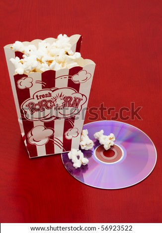 A bag of popcorn with a dvd and tickets on a wood background, movie and popcorn