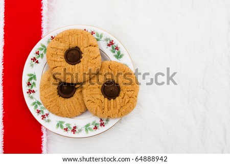 A plate of cookies with a red ribbon on a white fur background
