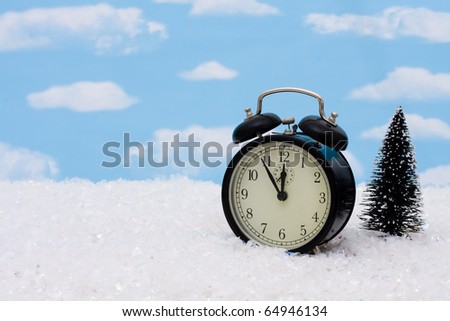 An alarm clock with a tree sitting on snow with a sky background, winter time