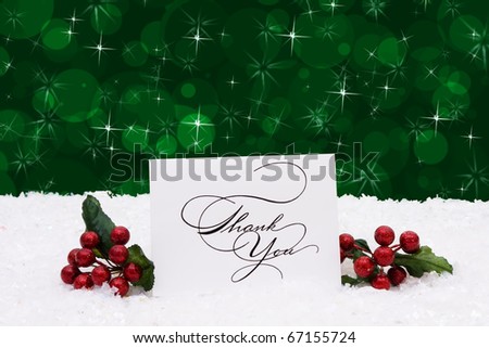 A thank you card sitting on snow with a green background, Christmas time