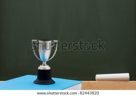 Trophy and book in front of a chalkboard with of copy space, Award winning education
