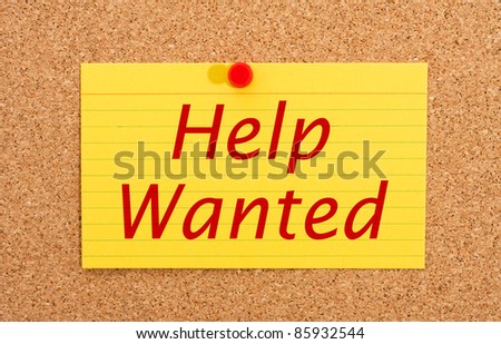 A yellow index card on a cork board with the words help wanted on it