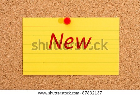 A yellow index card on a cork board with the word new on it, Announcing something new