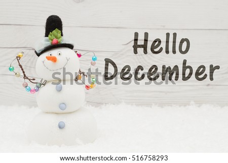 Hello December message, Some snow, Christmas ornaments and a snowman on weathered wood with text Hello December