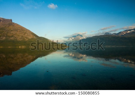 Norwegian fjord and mountains with clouds and reflection.