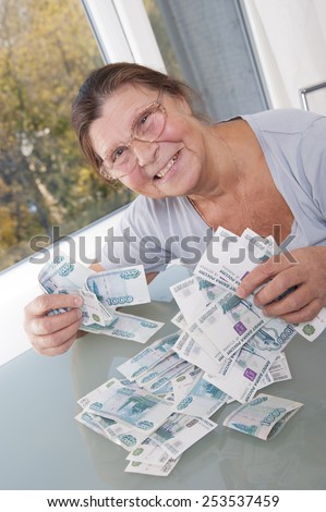 An elderly woman keeps a lot banknotes in denominations of one thousand rubles.