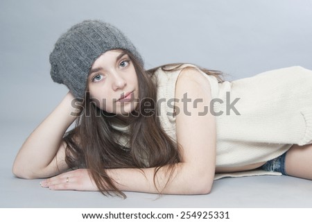 Young girl in a knitted hat lying on the floor.