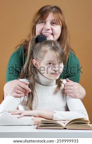 Woman hugging her daughter sitting with a book.