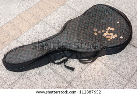 Street musician\'s guitar case with coins