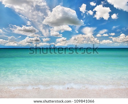Beautiful sea summer or spring abstract background. Golden sand beach with blue transparent ocean, white sailer and blue sky.