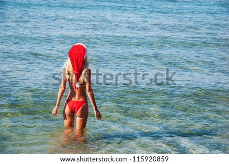 Beautiful woman in santa hat on the sea beach. The christmas or new year on the hot countries concept