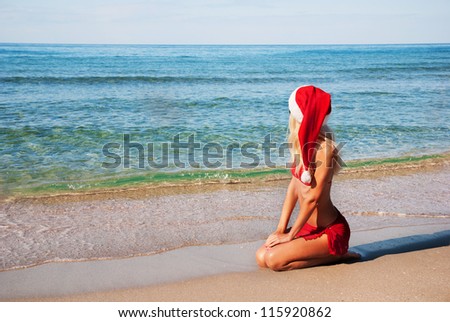 Beautiful woman in santa hat on the sea beach. The christmas or new year on the hot countries concept
