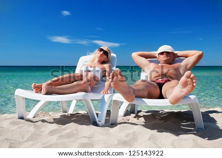 Young couple sunbathe on the beach bed on the sea beach