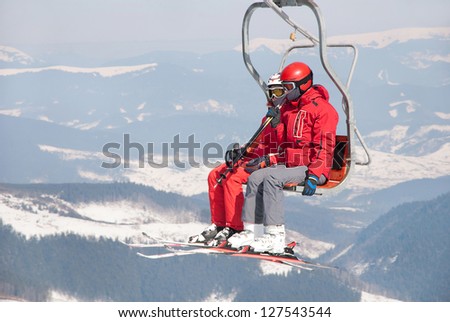Skiers couple on a ski lift in red skisuit