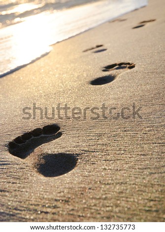 sand beach, wave and footsteps at sunset time