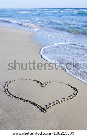 heart outline on the wet beach sand against sea wave