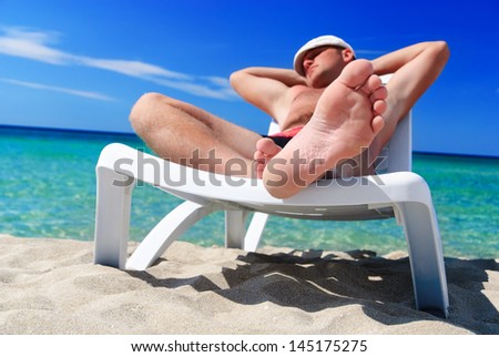 Young man in white cap sunbathe on beach bed at summer sea beach