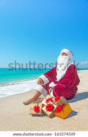 Santa Claus with many golden gifts relaxing on sandy sea beach - christmas or happy new year concept