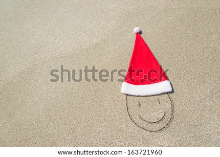 Santa Claus hat and smiley face on seashore against waves and blue sky - winter vacation concept