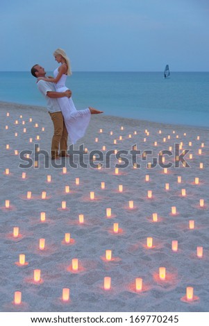 A man propose marriage to woman at sea beach in many candle lights against sunset- St.Valentines Day romantic concept