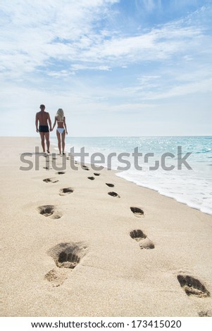 loving couple walking away with footprints at sea sandy beach