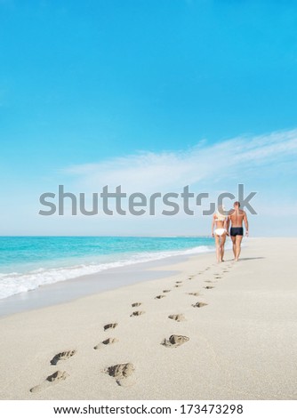 Loving Couple Walking Away With Footprints At Sea Sandy Beach