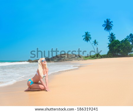 Cute blonde woman at ocean beach with palm trees
