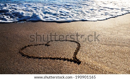 heart outline on the wet sand with wave brilliance foam