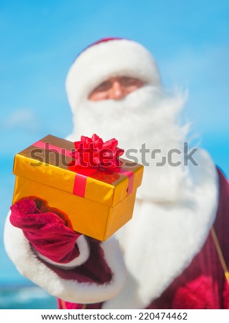 Santa Claus portrait with golden gift on sea beach - christmas or happy new year concept