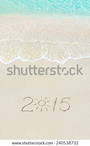 inscription 2015 on sea sand beach with the sun rays against wave foam and sky - vacation concept