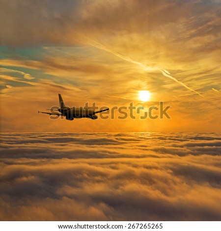 Airplane flight above stratum of clouds against golden bright sunset sky - air traffic concept or background