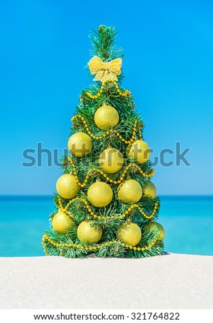 Christmas tree with golden decorations at tropical ocean beach. New Years vacation vertical background concept